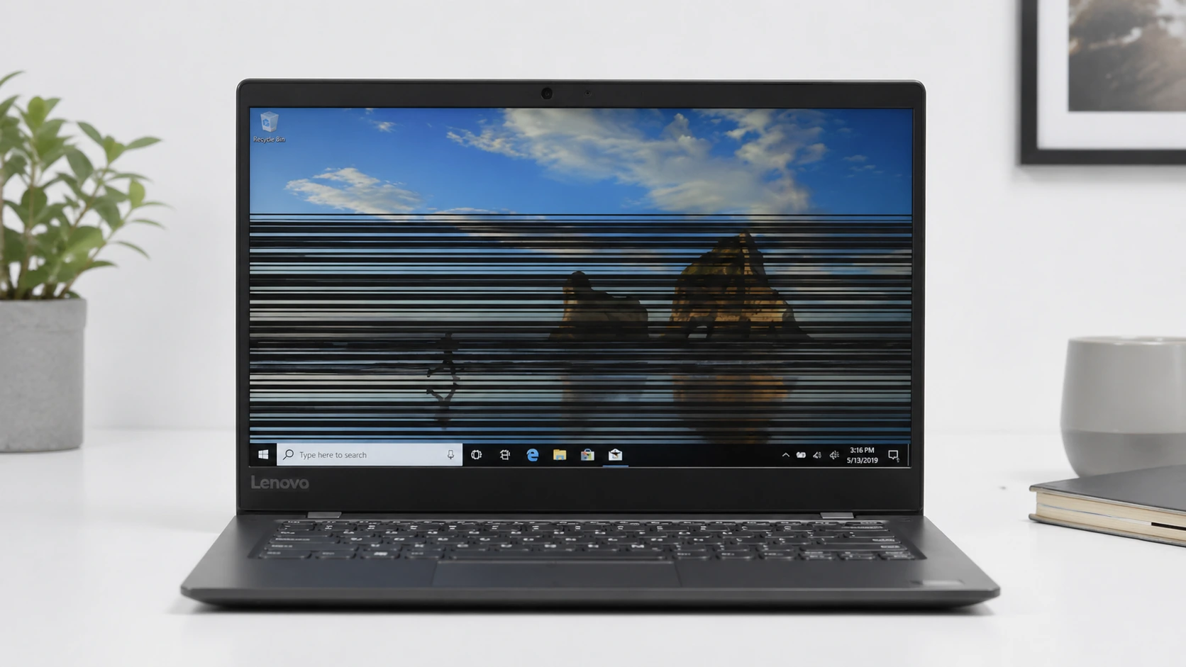 Lenovo laptop screen displaying horizontal flickering lines across the display panel on a desk