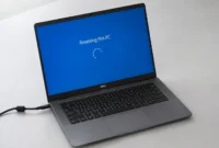 Dell laptop displaying a Windows "Resetting this PC" progress screen with power cable plugged in during a factory reset